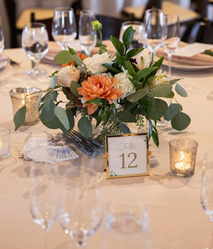Elegantly set table with floral centerpiece and table number 12 at a formal event.