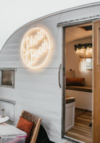 Vintage trailer converted into a photo booth with neon sign.