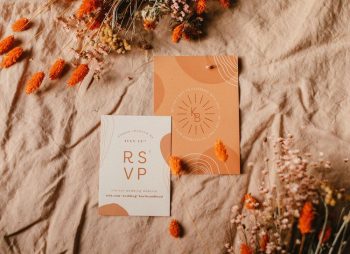 A wedding invitation and rsvp card surrounded by dried flowers on a textured cloth background.