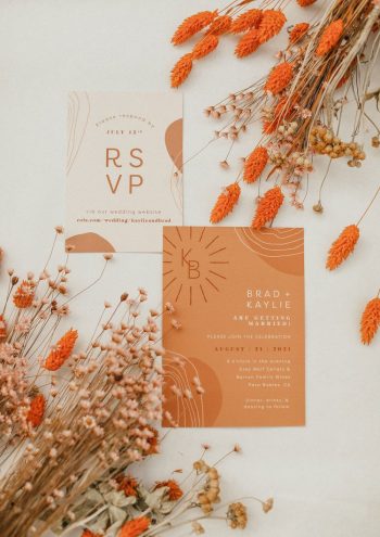 Elegant wedding invitation cards surrounded by decorative dried flowers.