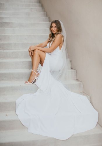 A bride sitting on steps in her wedding dress and veil.