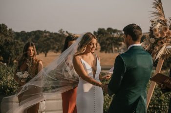 A bride and groom exchange rings at an outdoor wedding ceremony.