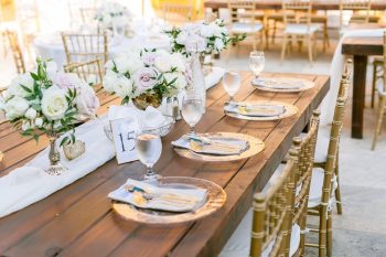 Elegantly set wedding reception table with floral centerpieces and gold chiavari chairs.