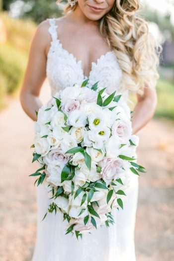Bride in a white dress holding a bouquet of white and pale pink flowers.
