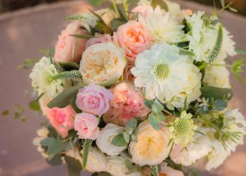 An arrangement of pastel flowers, including roses and chrysanthemums, with green foliage accents.