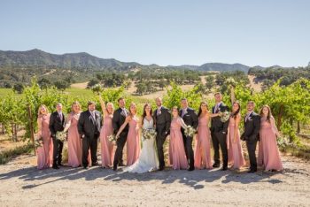 A bridal party posing for a photo at a vineyard.