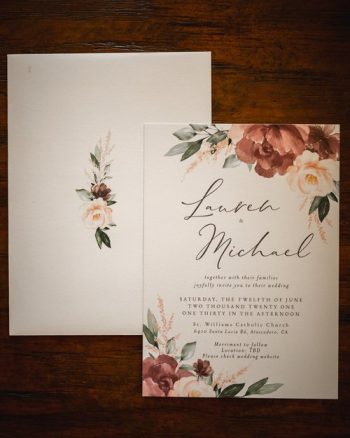Elegant wedding invitation with floral design on a wooden background.