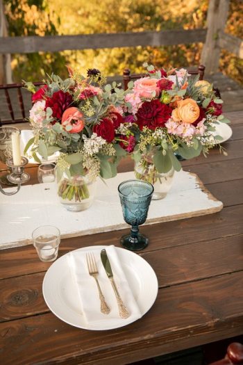 Elegant outdoor table setting with floral centerpiece and vintage dinnerware.