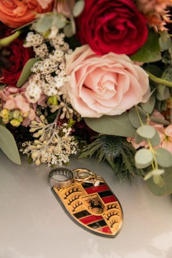 A close-up view of a floral arrangement featuring a variety of flowers, with a focus on a crest-shaped pendant nestled among the blooms.