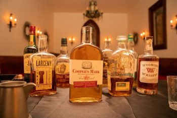 Assortment of whiskey bottles on a table with ambient lighting.