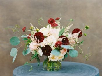 An elegant floral arrangement in a glass vase on a blue surface.