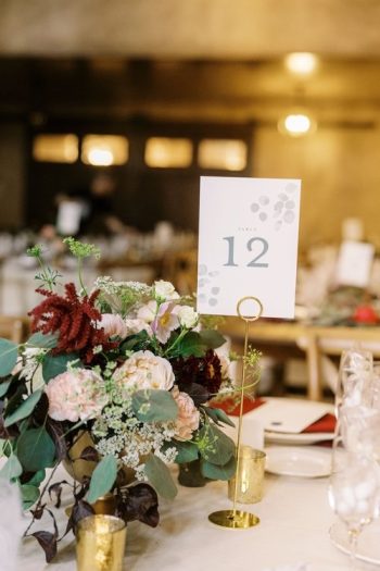 Elegant table setting with a number 12 sign and a floral centerpiece at a formal event.