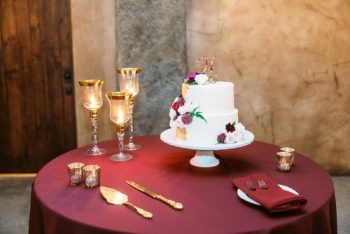 A wedding cake on a table with floral decorations and elegant glassware.