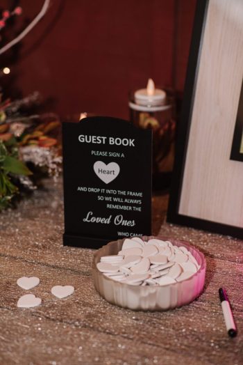 A guest book station with heart-shaped tokens for signatures at an event.