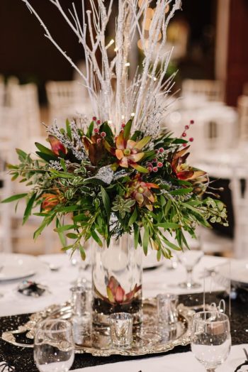Elegant table centerpiece with twinkling branches and vibrant flowers at a formal event.