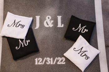 Two pairs of white and black cloth napkins embroidered with "mr" and "mrs" on a surface featuring the initials "j & l" and a date "12/31/22.