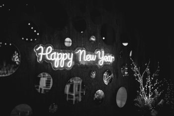 Neon 'happy new year' sign illuminated against a dark backdrop with circular cutouts.