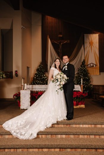 A couple in wedding attire posing for a photo in a festively decorated venue with a christmas theme.