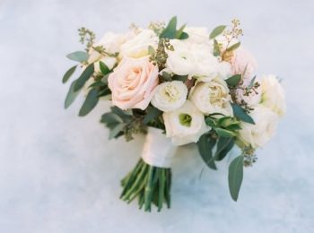 A bridal bouquet featuring a mix of pink and white roses and assorted greenery.