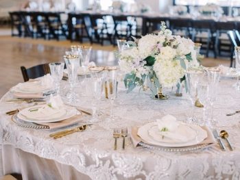 Elegant dining table set for a formal event with floral centerpiece and gold-trimmed tableware.