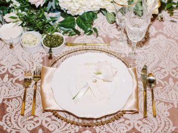 Elegant table setting for a formal event with floral centerpiece, gold cutlery, and a menu card.