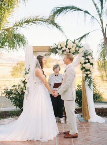 Bride and groom holding hands at an outdoor wedding ceremony.