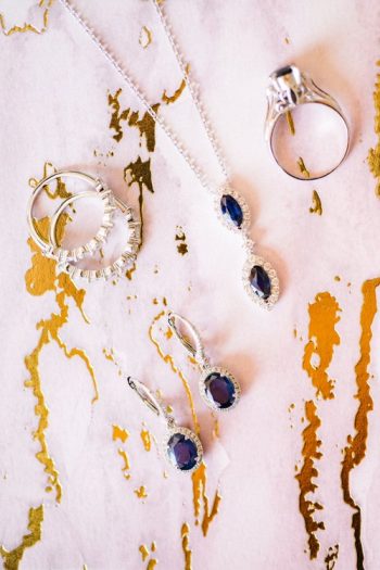 Elegant jewelry with blue gemstones displayed on a textured background with gold accents.