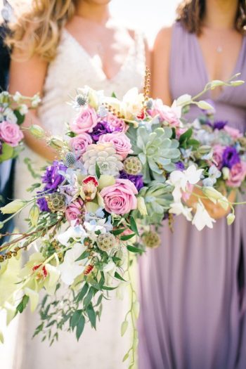 Bridesmaids holding a bouquet of flowers with a mix of succulents and blooms in pastel shades.