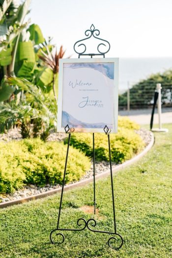 A welcome sign for jessica and jonathan's event, displayed on an easel outdoors with a scenic backdrop.
