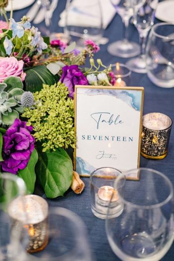 Elegant event table setting with floral centerpiece and table number card.