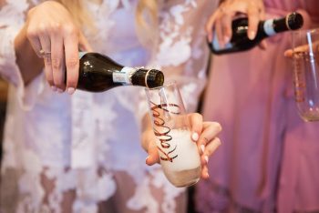Pouring champagne into a glass with "cheers" written on it.
