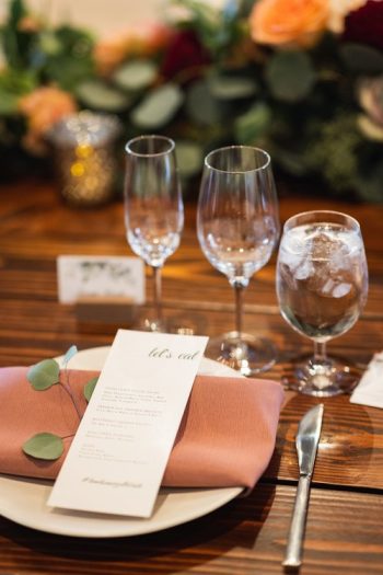 An elegant table setting with a menu, cutlery, and glassware for a formal event.
