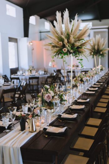 Elegantly set long dining tables with floral centerpieces in a modern event space.