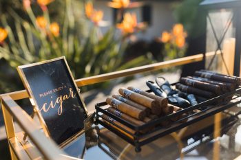 A selection of cigars on a tray with a sign saying "please enjoy a cigar".