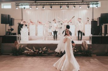 Bride dancing joyously in front of a live band at a wedding reception.